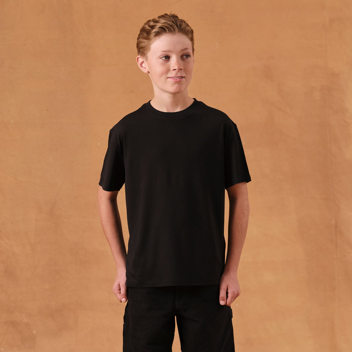 The Kids T-Shirt S/S in black soft merino wool, model wearing front view [model: vincent | size: 11-12 yrs]