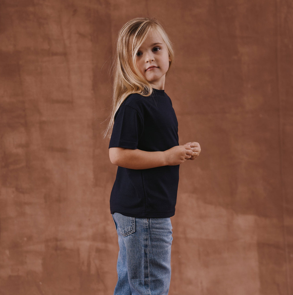 The Kids T-Shirt S/S in black soft merino wool, model wearing back view [model: philine | size: 3-4 yrs]