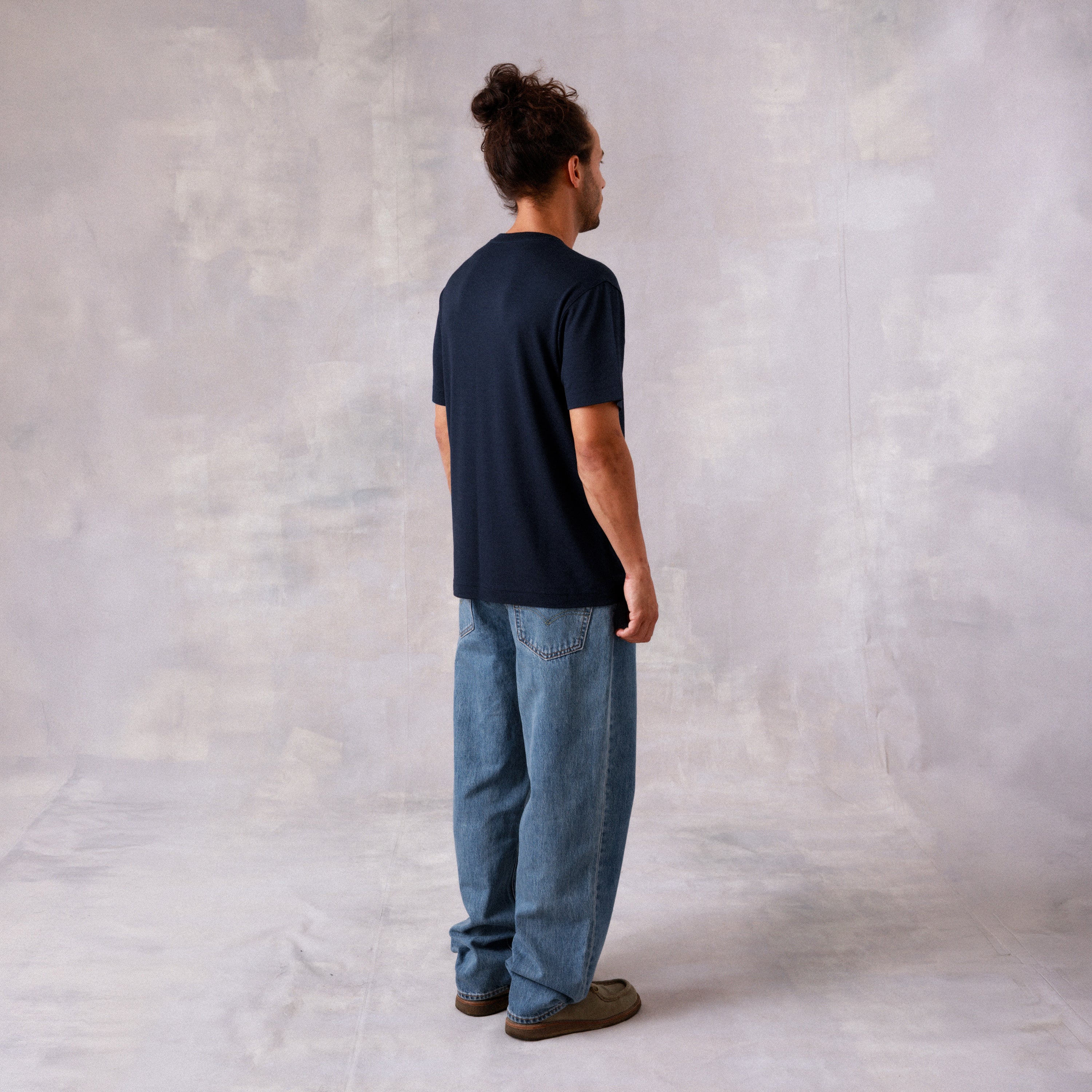 The Regular T-Shirt in blue extrafine merino wool, model wearing back side view