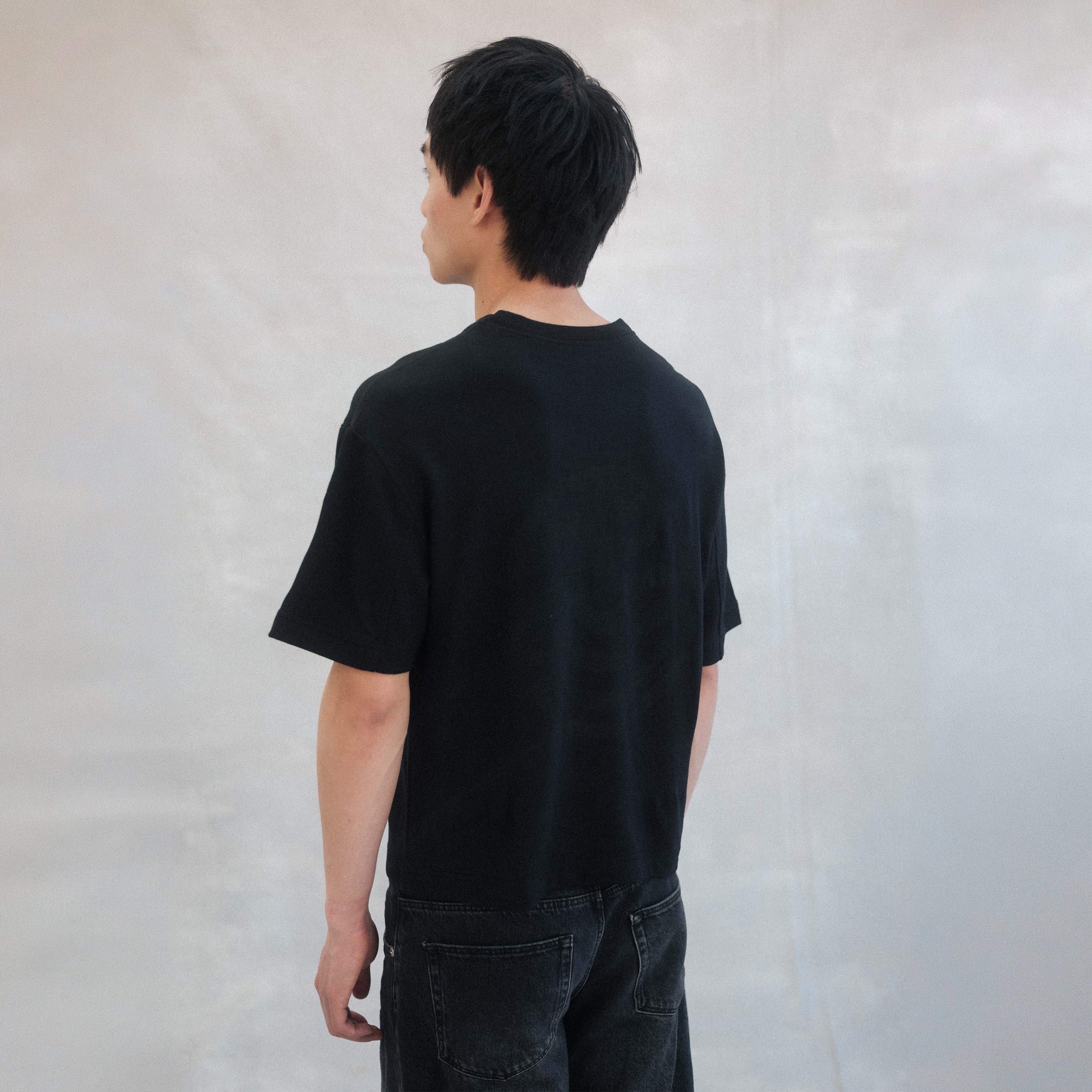 The Box Tee in black heavy merino wool, model wearing side view