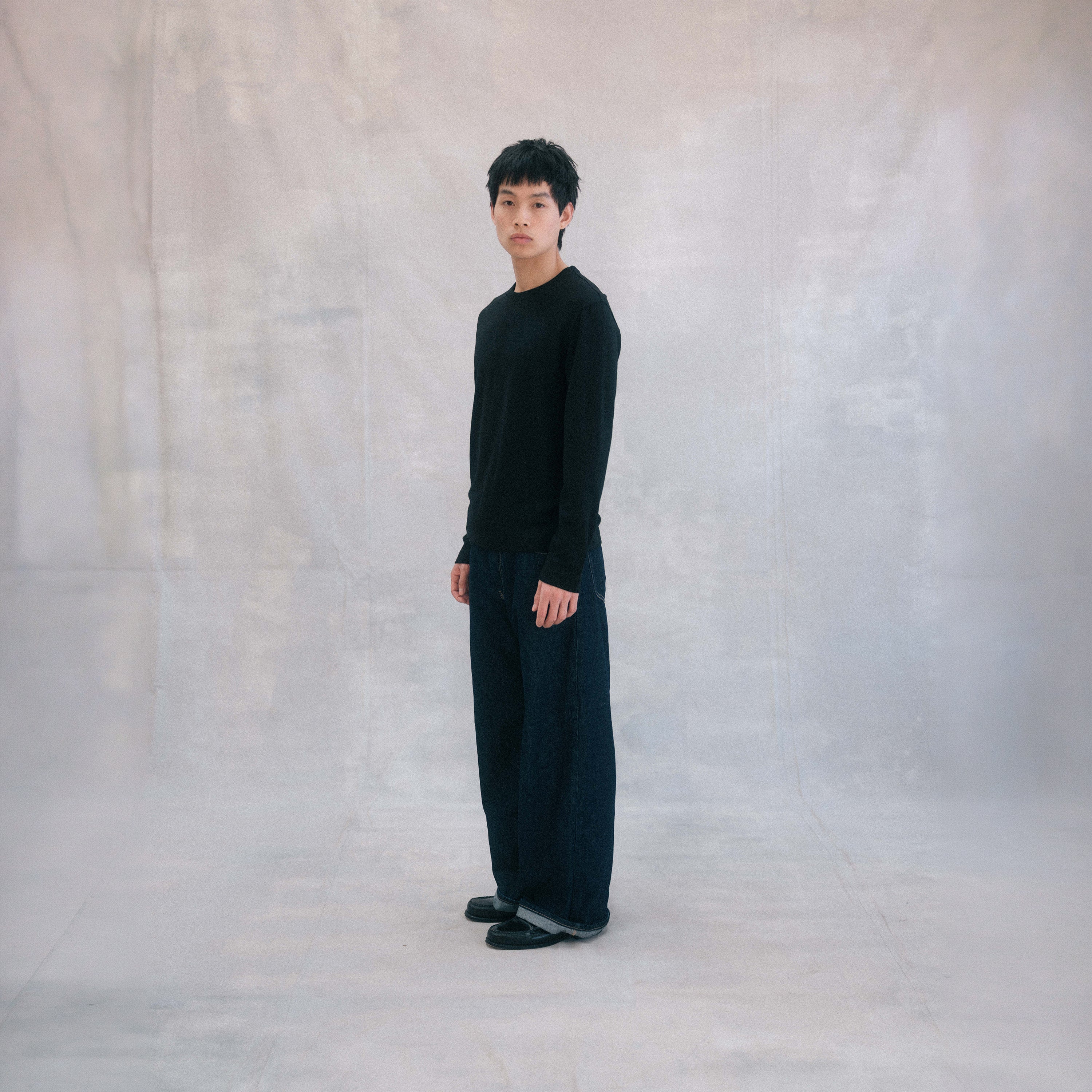 The Regular T-Shirt L/S in black extrafine merino wool, model wearing side view